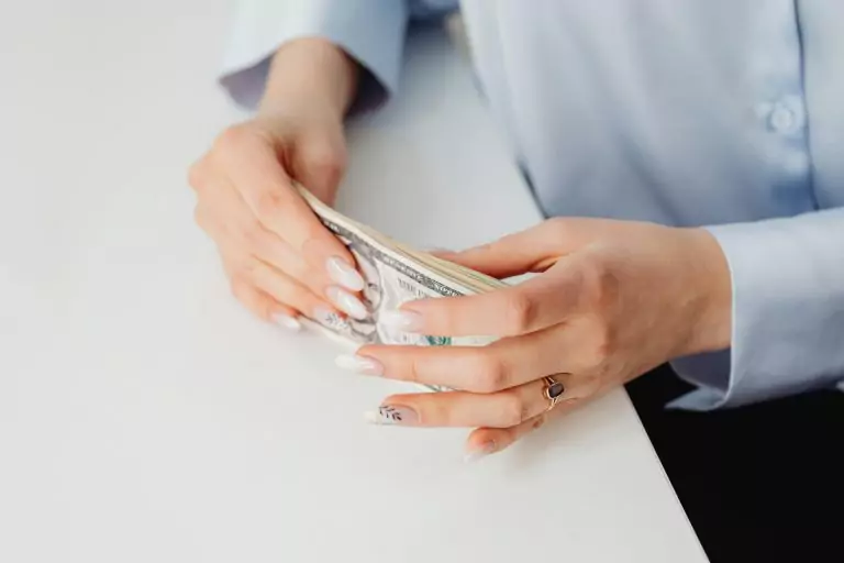 Close-up of hands holding US dollar bills showcasing minimum wage